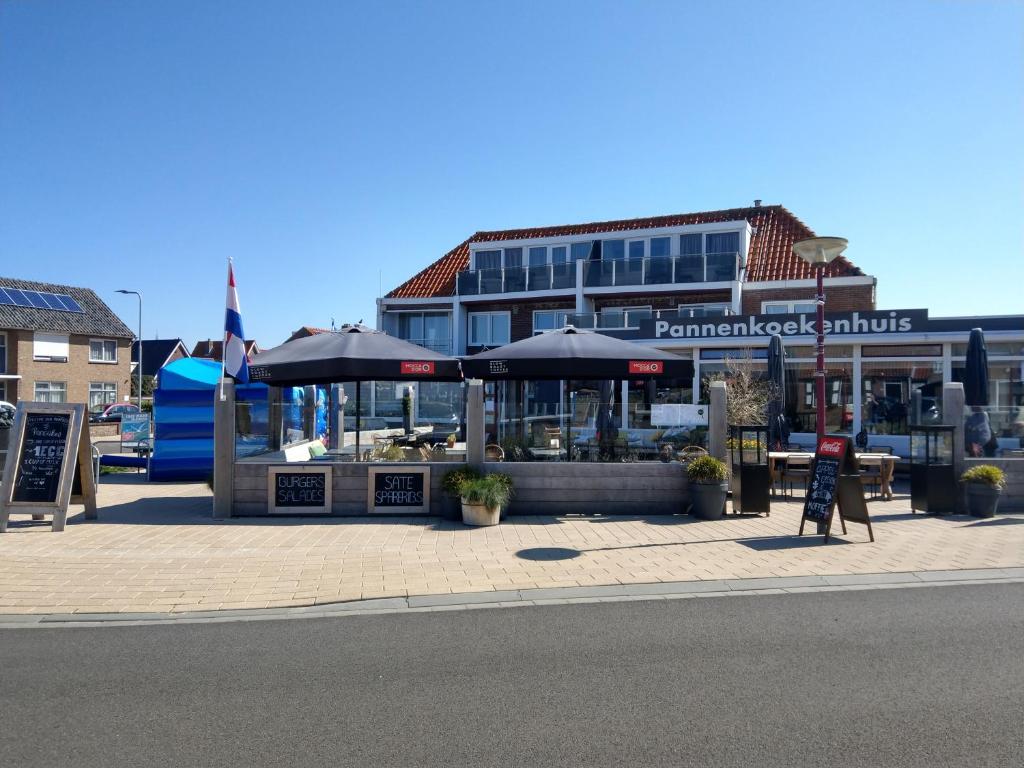 restauracja z parasolami przed budynkiem w obiekcie Appartement aan het strand De Zeemeermin w mieście Zoutelande