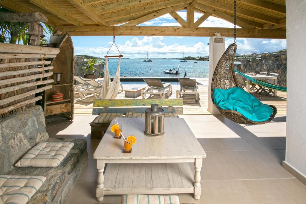 a patio with a table and a hammock and the water at MA CABANE PIEDS DANS L EAU in Cul de Sac