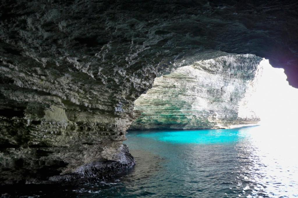 a cave with a blue pool of water at Résidence hôtelière A TRAMA in Bonifacio