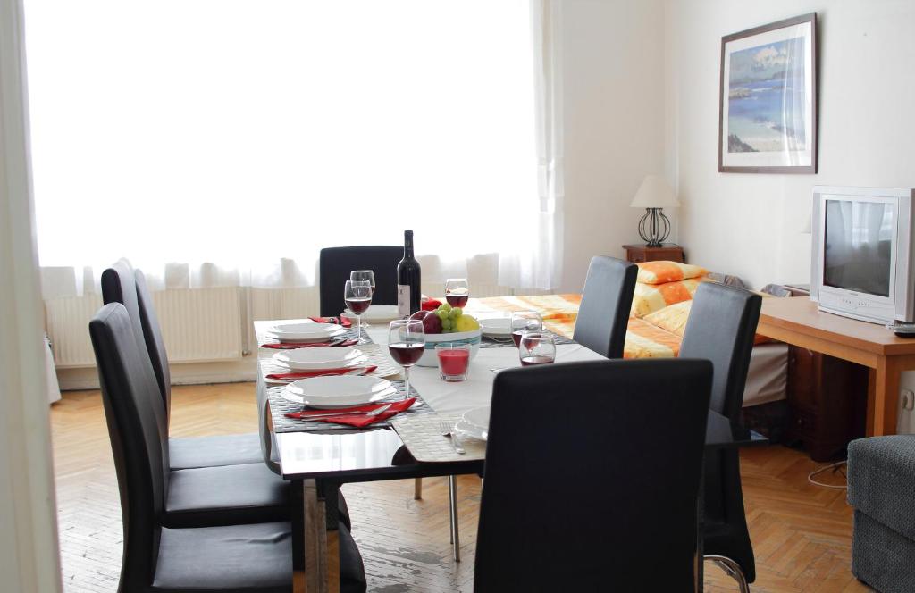 a dining room table with black chairs and a table with wine glasses at Blue Rose Apartment in Budapest