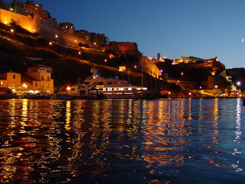 a body of water with a city at night at Résidence hôtelière A TRAMA in Bonifacio