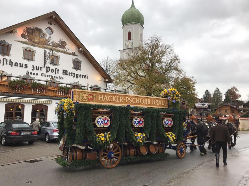 un carruaje tirado por caballos conduciendo por una calle en Metzgerei Gasthof Oberhauser - Hotel zur Post, en Egling