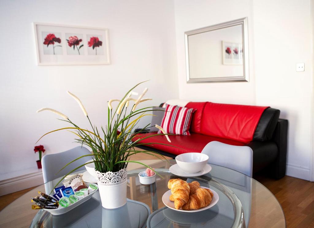 a living room with a glass table and a red couch at Apt 1, Opera House 2nd Floor by Indigo Flats in London