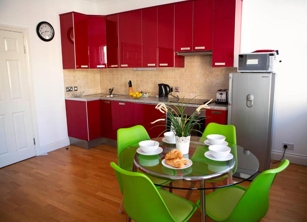 kuchnia z czerwonymi szafkami i stołem z zielonymi krzesłami w obiekcie Apt 2, Opera House by Indigo Flats w Londynie