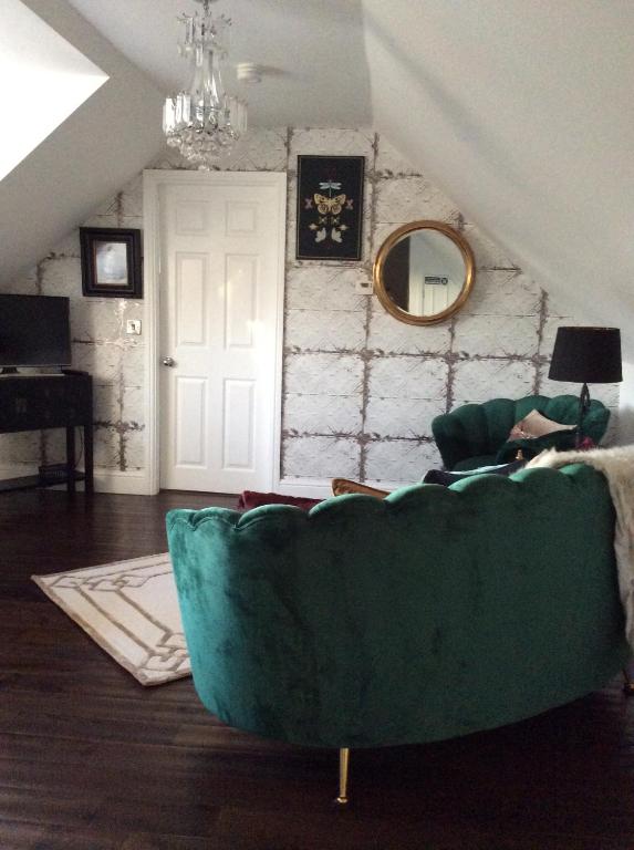 a living room with a green couch and a mirror at Holly Tree Cottage in High Etherley