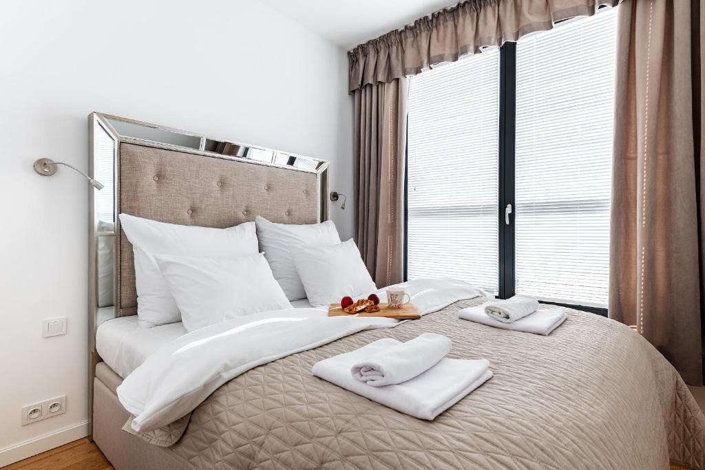 a bedroom with a large bed with towels on it at Airport Lirowa - P&O Serviced Apartments in Warsaw