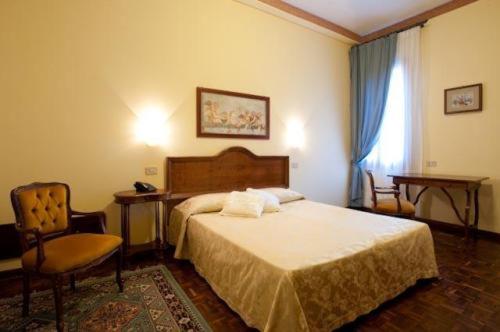 una camera con un letto e una sedia e una finestra di Hotel Florida a Venezia