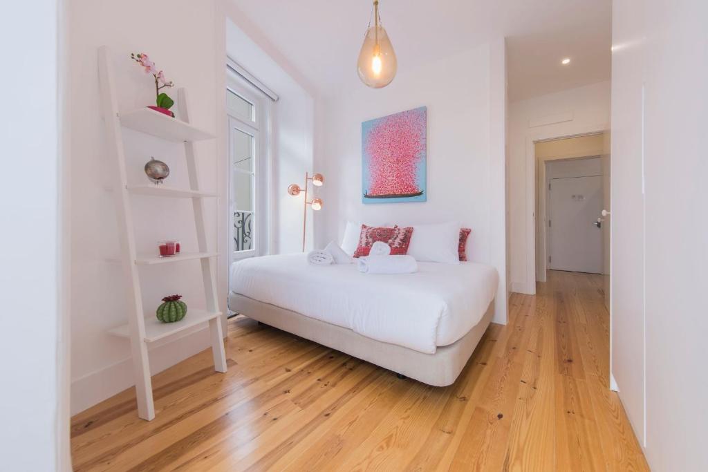 Habitación blanca con cama blanca y suelo de madera. en LovelyStay - Lusitano's Heart 2BDR Apartment in Alfama, en Lisboa