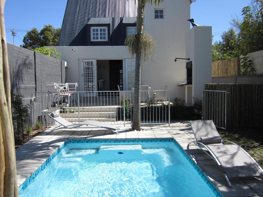 a swimming pool in front of a house at Quainton Cottages in Hermanus