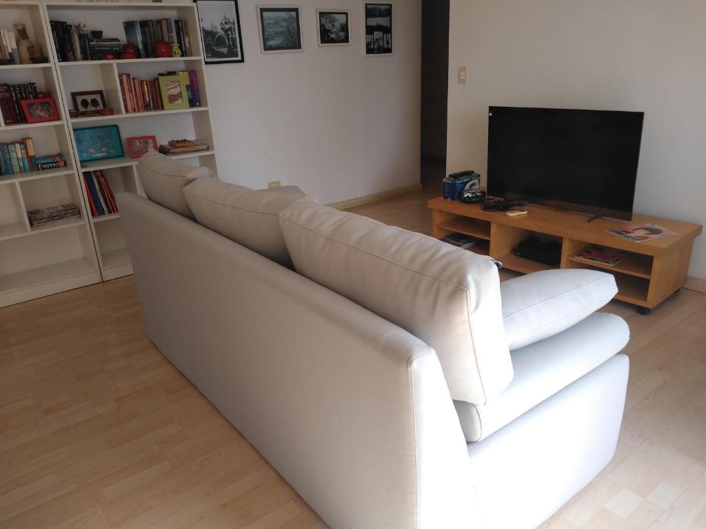 um sofá branco numa sala de estar com televisão em cerviño nuevo em Buenos Aires