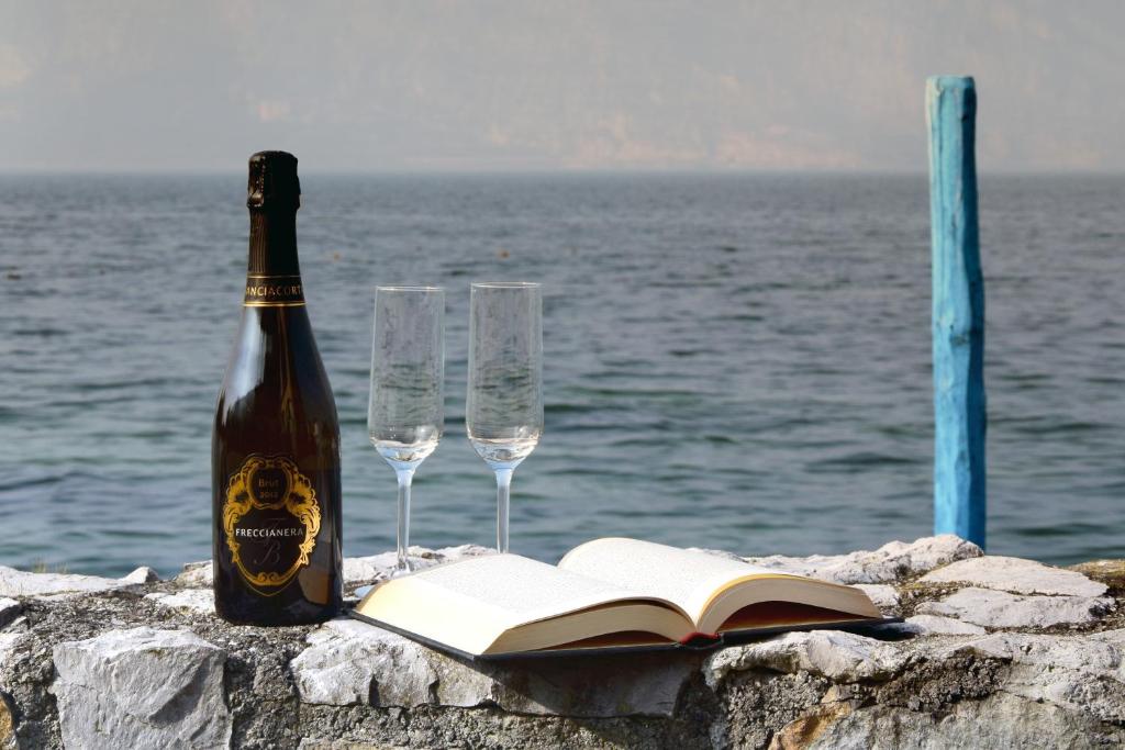 uma garrafa de vinho e dois copos e um livro aberto em IN SUITE LAKE 2 em Iseo