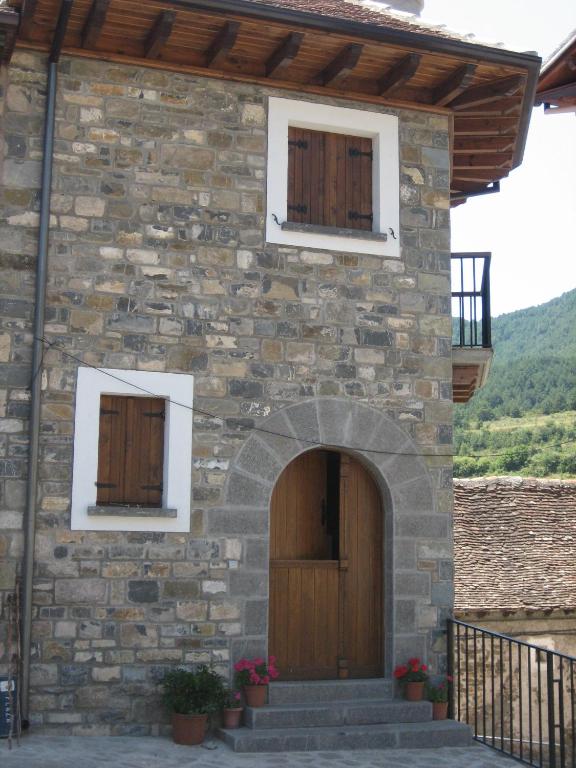 a stone building with two windows and a wooden door at Casa Magdalena Autural in Siresa