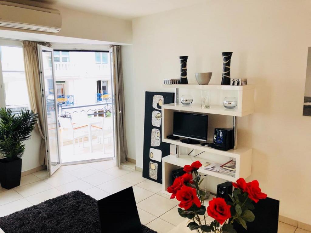 - un salon avec une télévision et des fleurs rouges sur une table dans l'établissement Ô Palais des Iles Two Bedroom Cannes, à Cannes