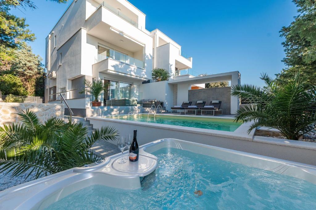 eine Villa mit einem Pool und einem Haus in der Unterkunft Luxury apartment SUNSET with private pool and jacuzzi in Novalja