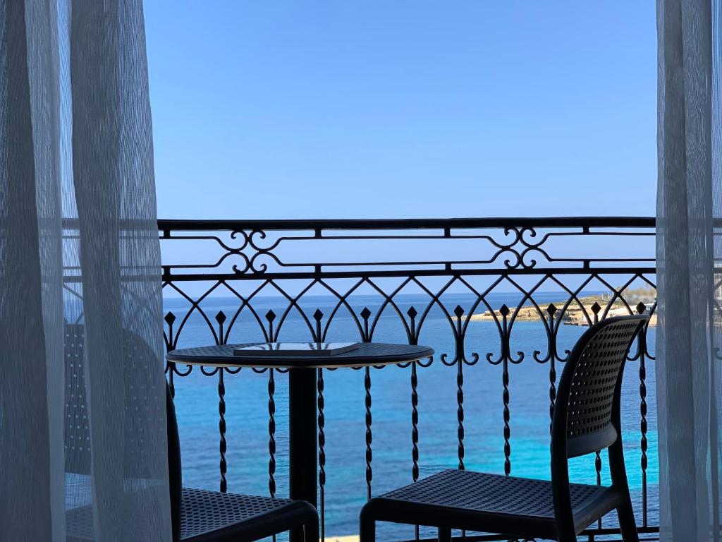 a balcony with a table and chairs and the ocean at Ascot By The Sea in St. Paul's Bay