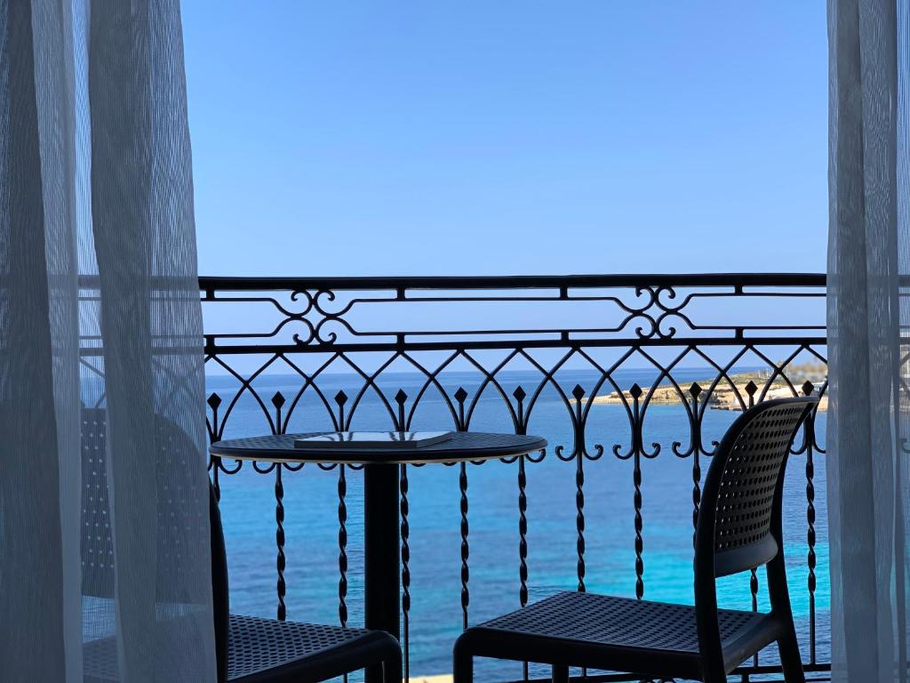 balcone con tavolo, sedie e vista sull'oceano di Ascot By The Sea a San Pawl il-Baħar
