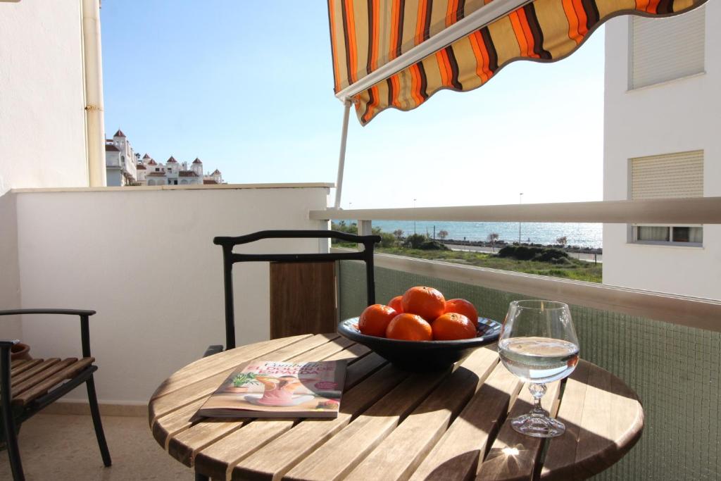 a table with a bowl of fruit and a glass of wine at Beach and Family in Vélez-Málaga