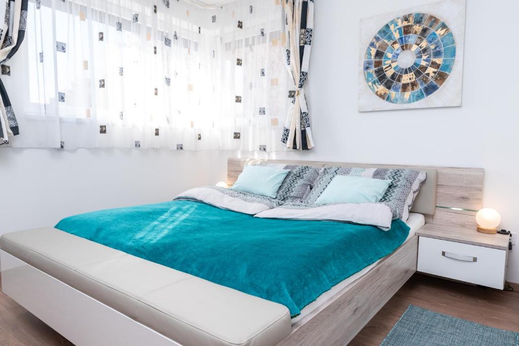 a bedroom with a bed with a blue blanket at Defne Apartman in Debrecen