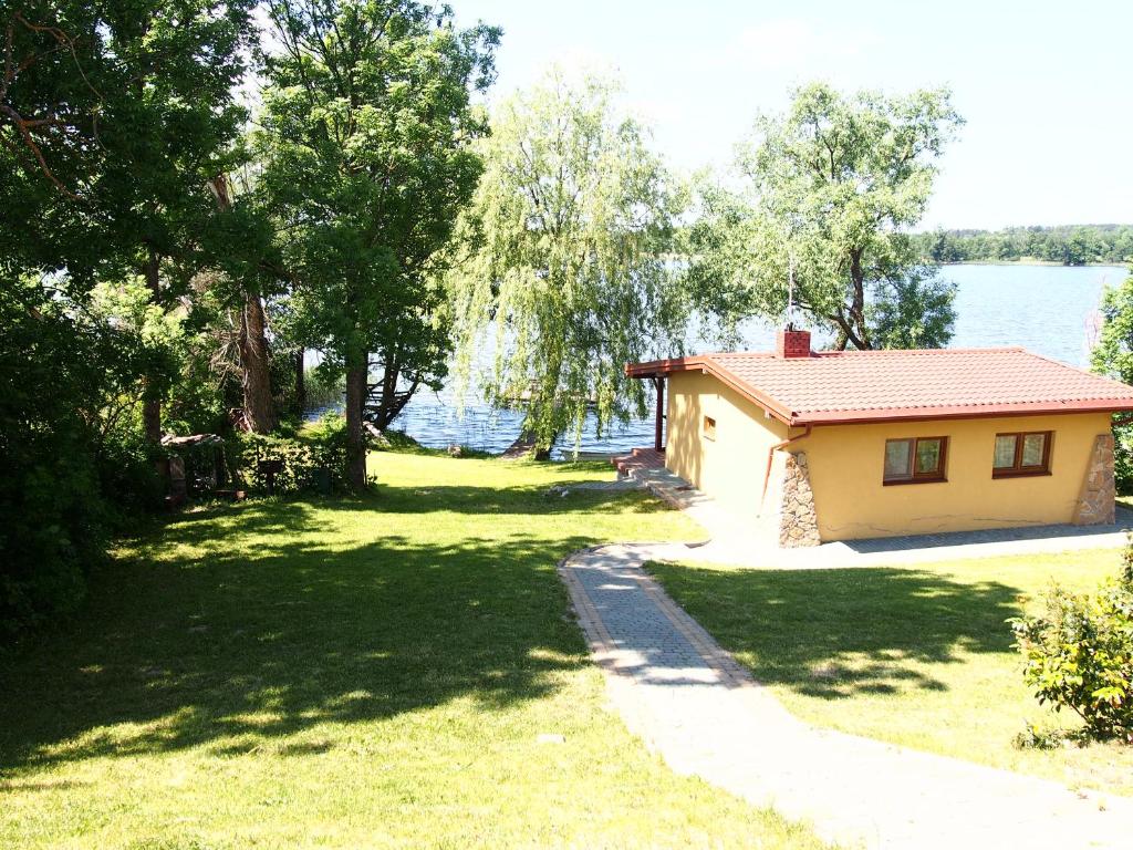 ein kleines Haus im Gras neben dem Wasser in der Unterkunft ZELWAGI 14 in Mikołajki