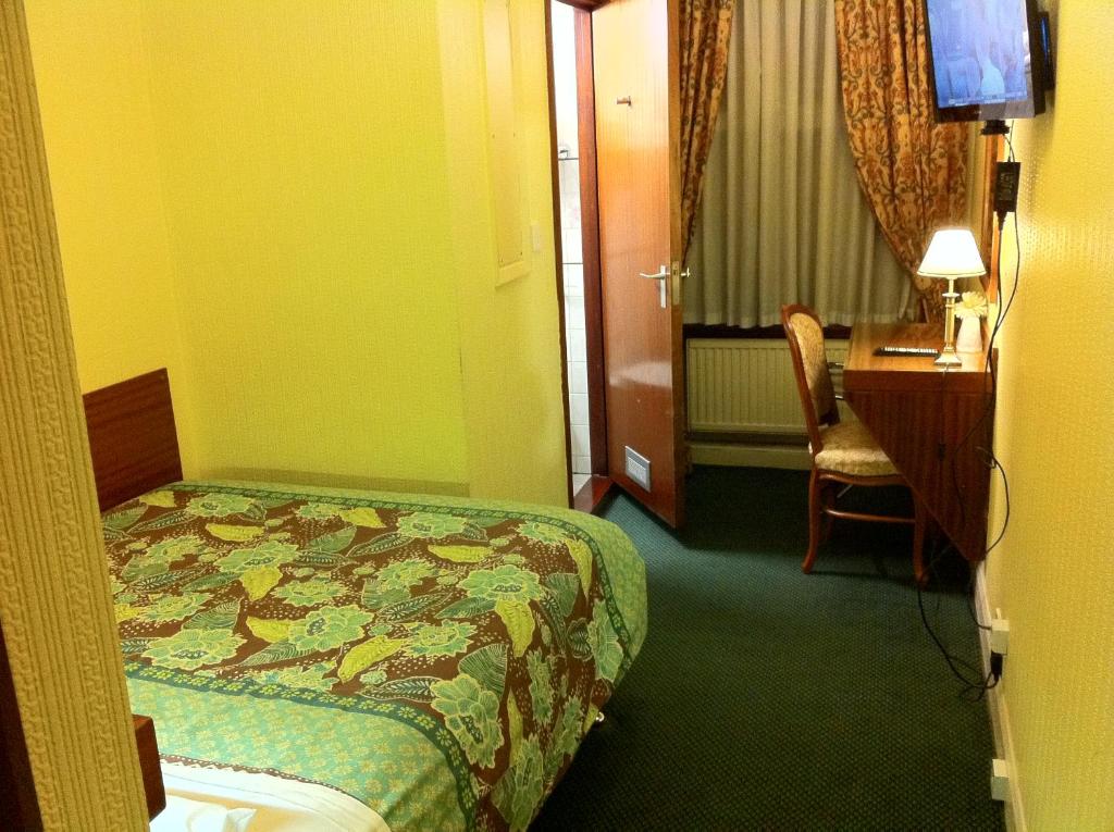 a hotel room with a bed and a desk and a desk at London Visitors Hotel in London