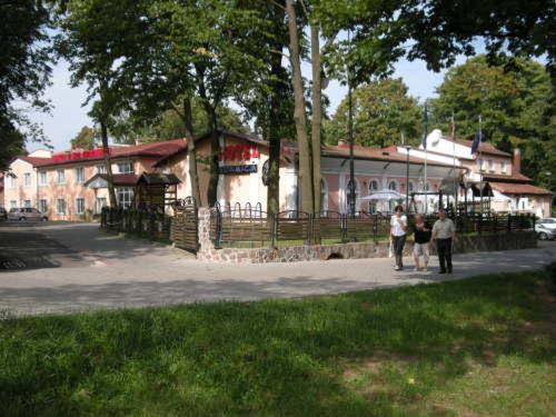 a group of people walking on a sidewalk near a building at Hotel Colosseum in Olecko