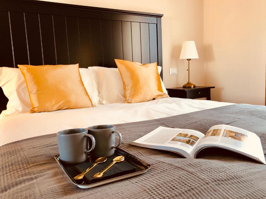 una bandeja con dos tazas y un libro en una cama en Casa Ciampi Locazione Turistica, en Pisa