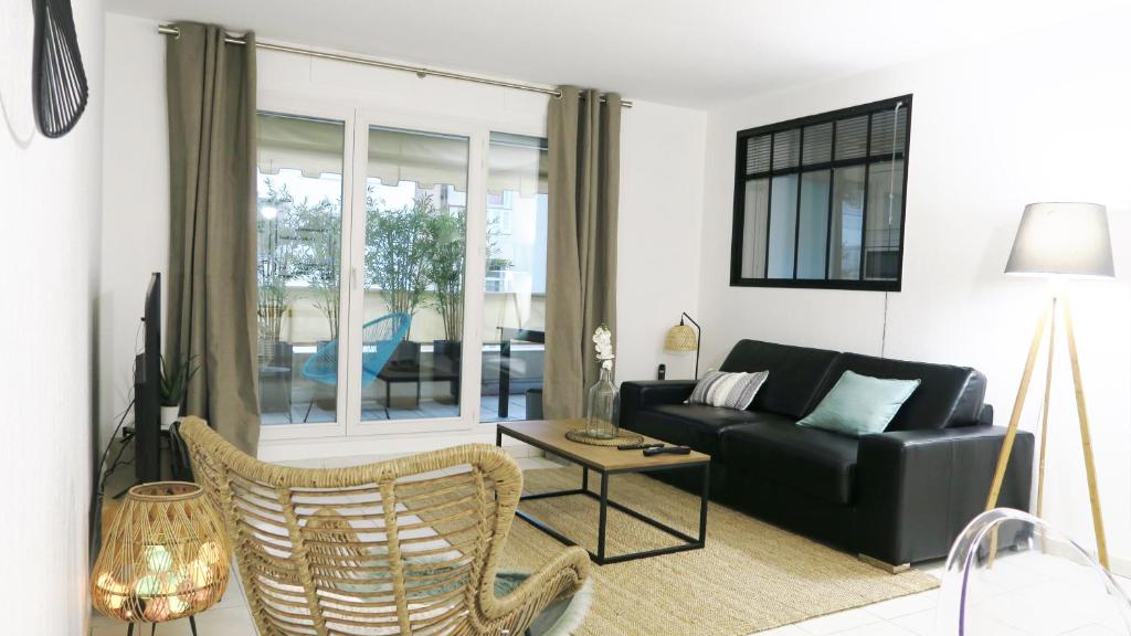 a living room with a black couch and a table at Appartement Palais Milton in Cannes