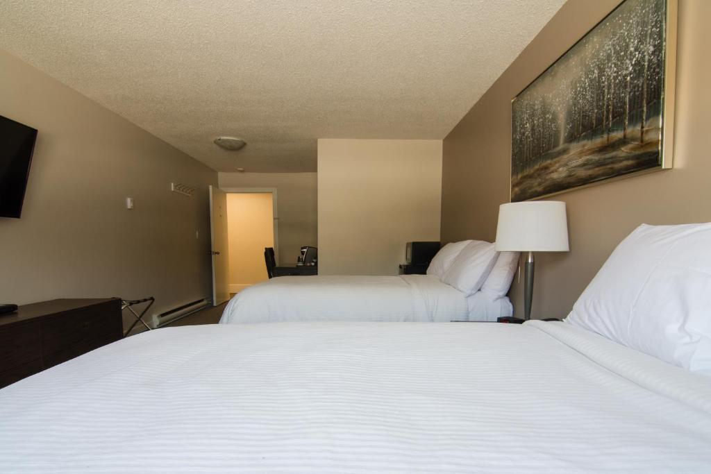 a hotel room with two beds and a tv at Northwood Plaza Hotel in Prince George