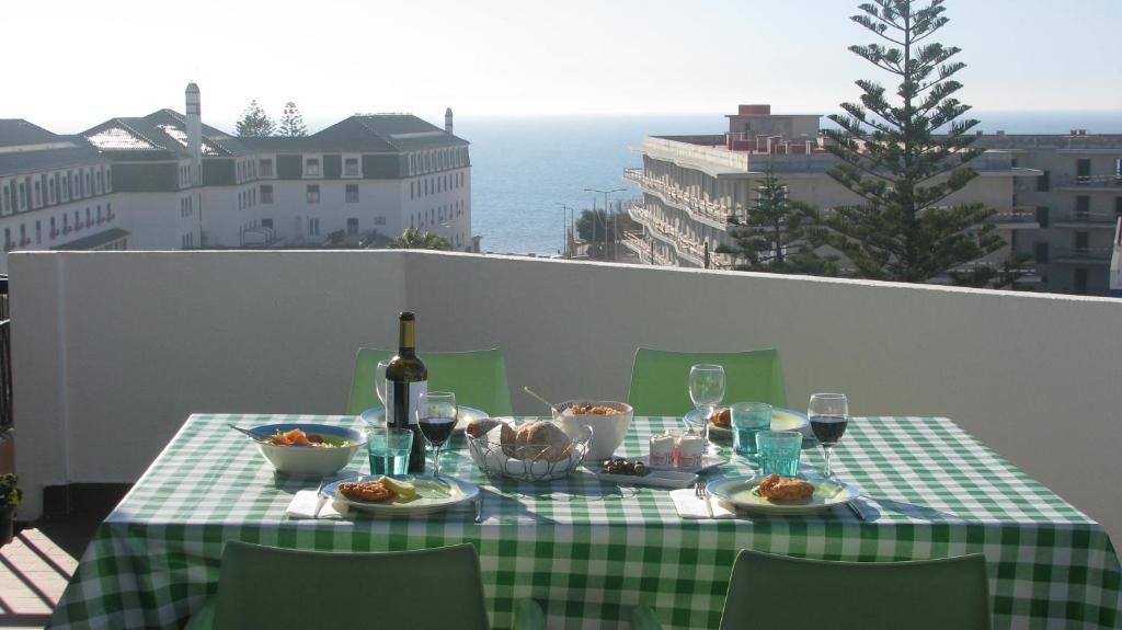 una mesa con un mantel verde y blanco a cuadros con comida y vino en Casa da Baleia Ericeira, en Ericeira