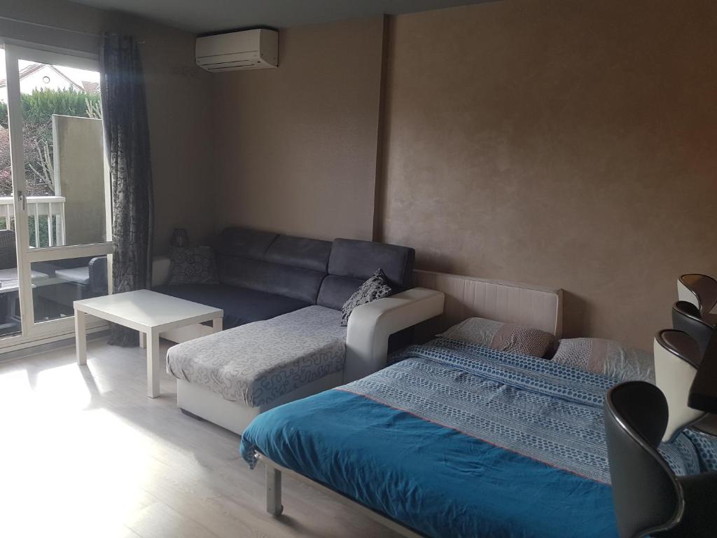 ein Wohnzimmer mit einem Sofa und einem Bett in der Unterkunft studio meublé avec balcon in Arcueil