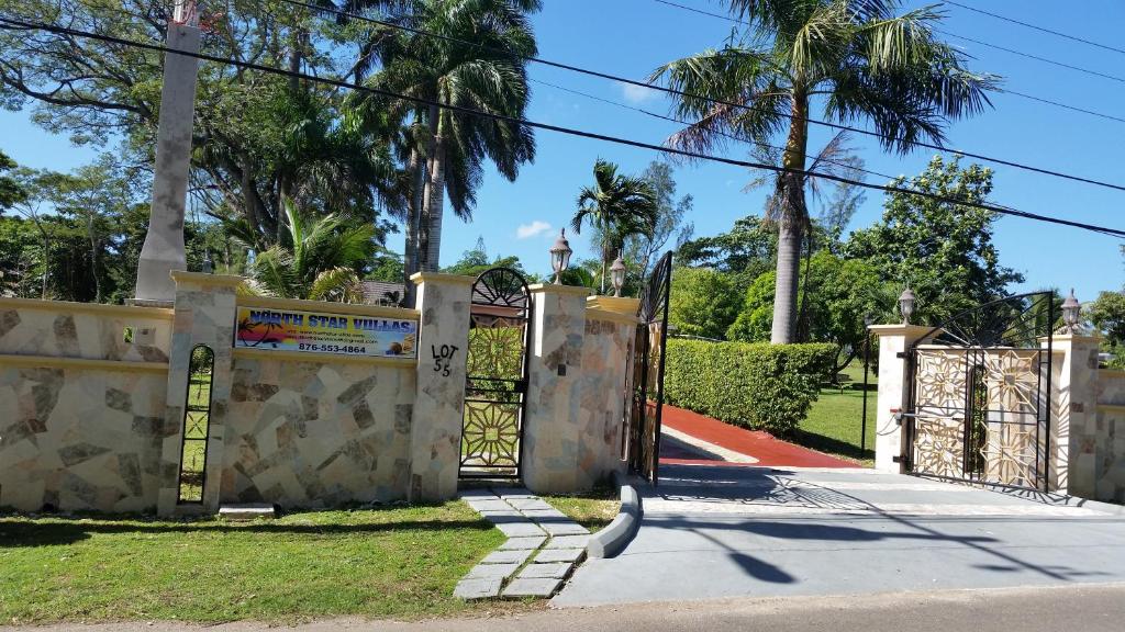 a gate to a driveway with palm trees at North Star Villas in Ocho Rios