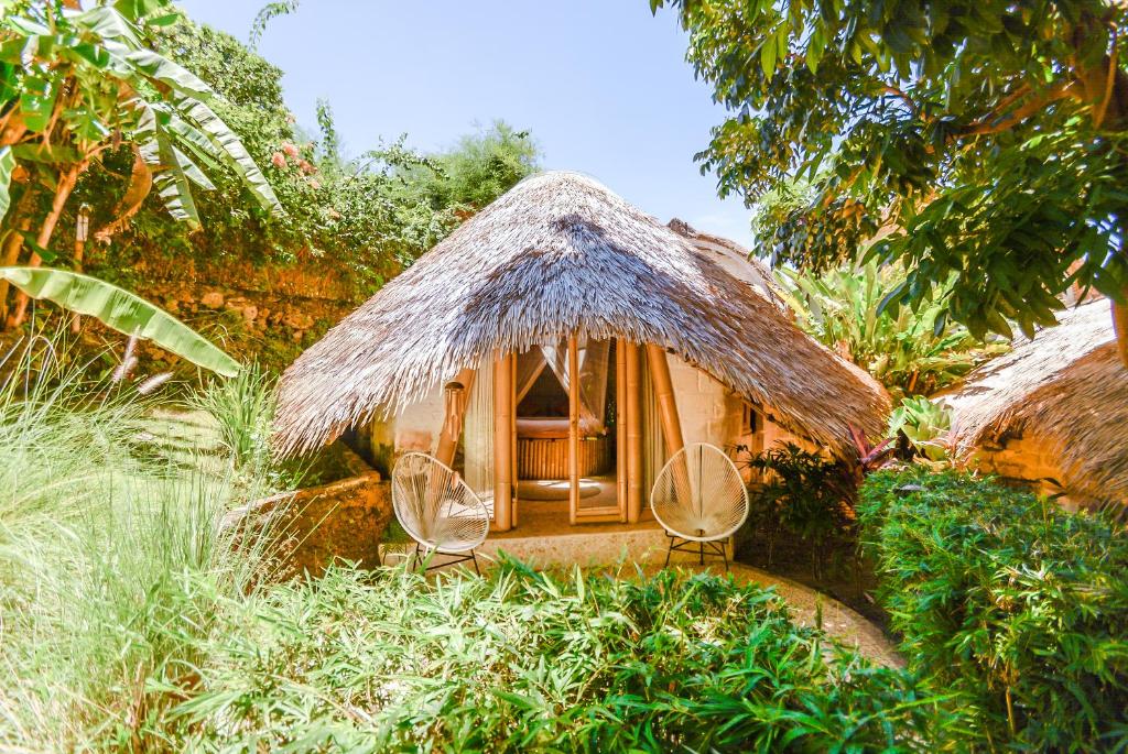 une petite maison avec deux chaises et un toit de chaume dans l'établissement Le Bamboo Bali, à Uluwatu