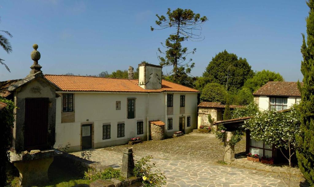 a large white house with a cobblestone driveway at Pazo Cibrán in San Xulián de Sales