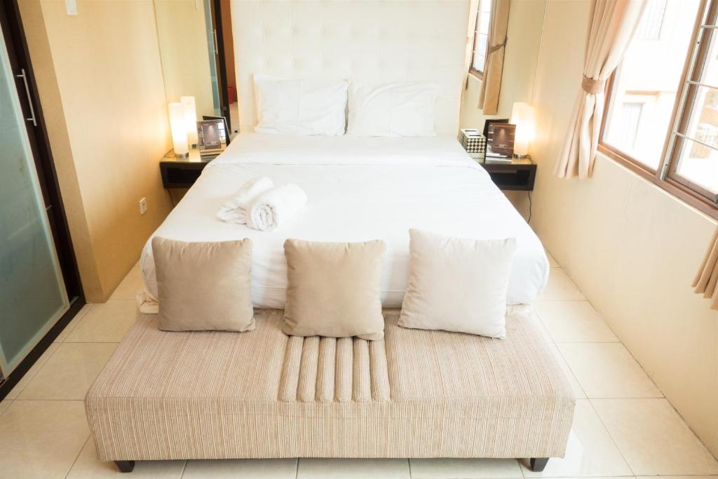 a bedroom with a large bed with white sheets and pillows at Antique 3BR at Grand Setiabudi Apartment By Travelio in Bandung