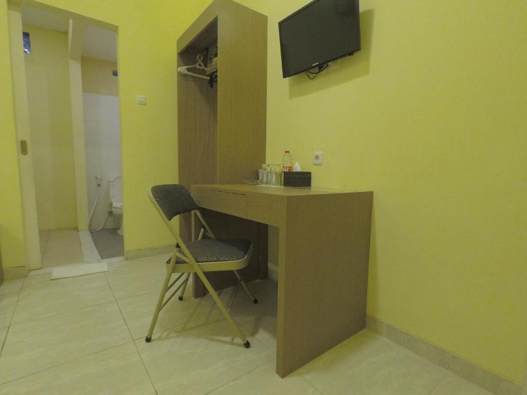 Zimmer mit einem Schreibtisch und einem TV an der Wand in der Unterkunft Muara Inn ternate in Ternate