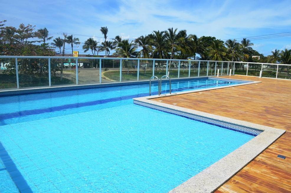 einen großen Pool mit Holzterrasse und einem Zaun in der Unterkunft Solaris Residencial Clube in Ilhéus