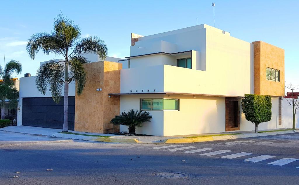 une maison blanche avec des palmiers devant elle dans l'établissement Suites Lagunas, à Colima