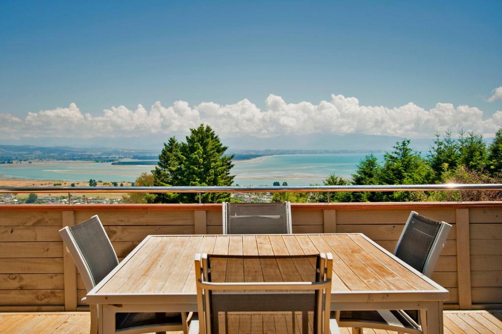 una mesa de madera y sillas en una terraza con vistas en Commodore Holiday Home, en Nelson