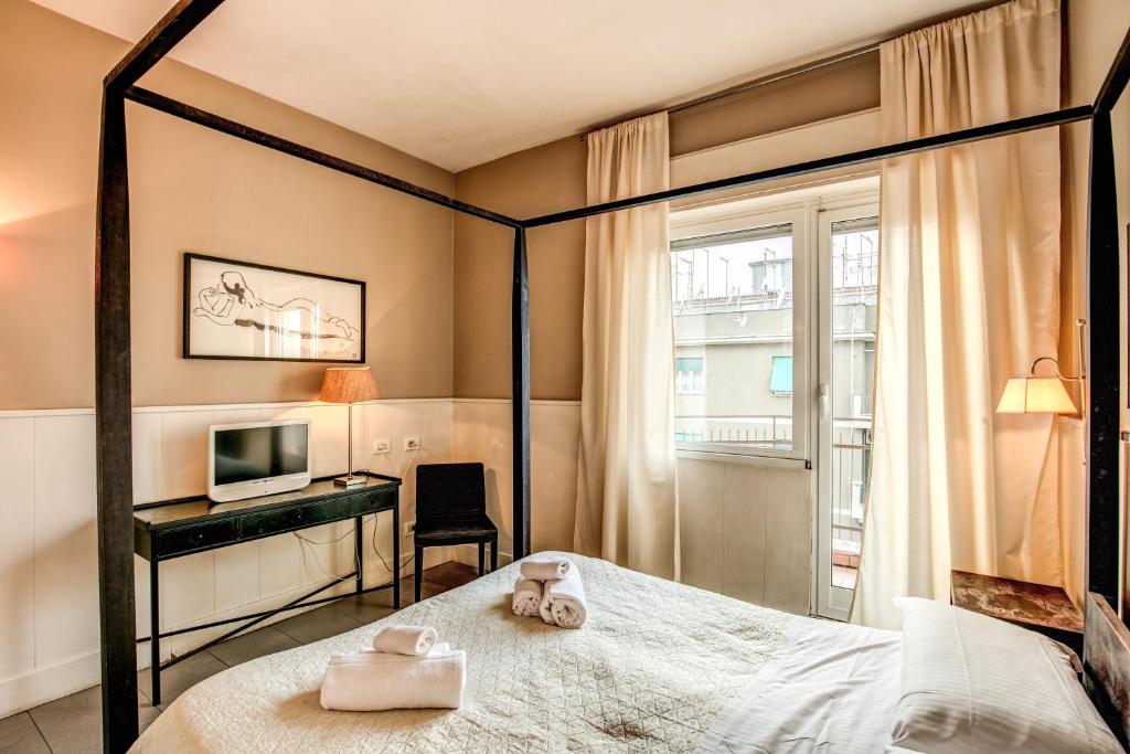 sypialnia z łóżkiem, biurkiem i telewizorem w obiekcie City Guest House w Rzymie