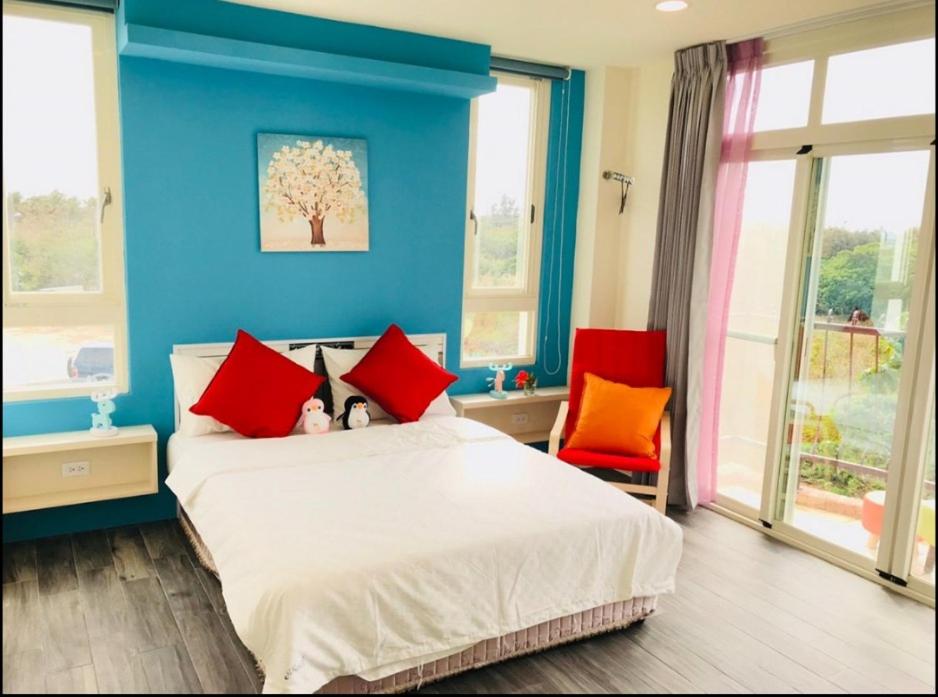 a blue bedroom with a bed and two red chairs at Full Moon Resort in Hengchun