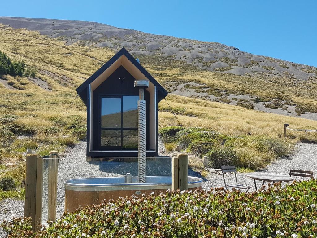 a small building with a mirror on a hill at Lake Stella Mountain Huts in Mt Lyford