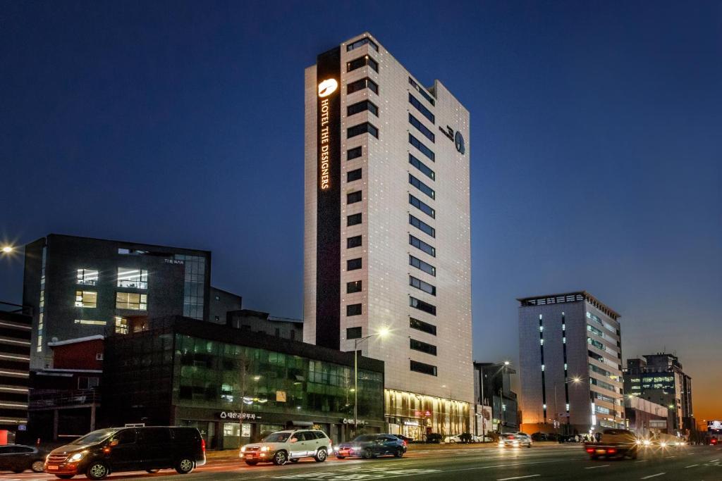 un edificio alto con coches estacionados en una ciudad en Hotel The Designers Hongdae en Seúl