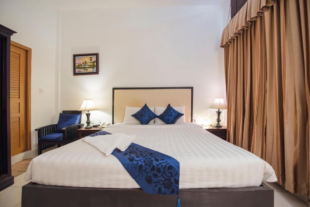 een slaapkamer met een groot bed met blauwe kussens bij Homesyn Hotel in Phnom Penh