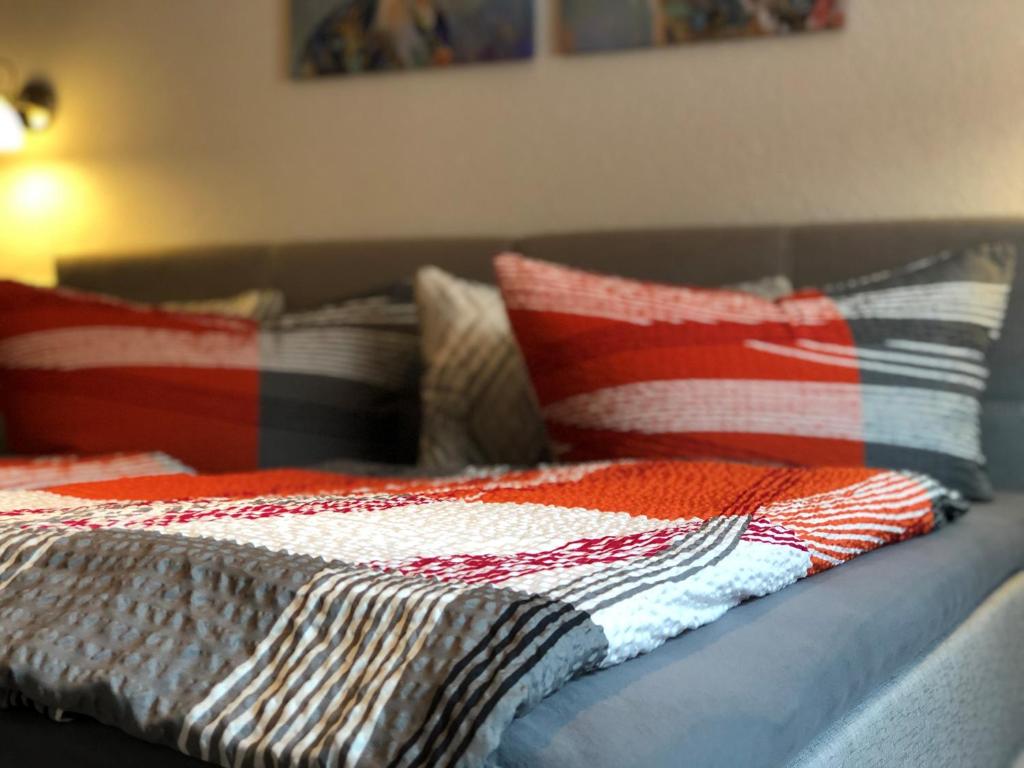 a bed with a red and white blanket and pillows at Pension "Tor zum Rennsteig" in Hörschel