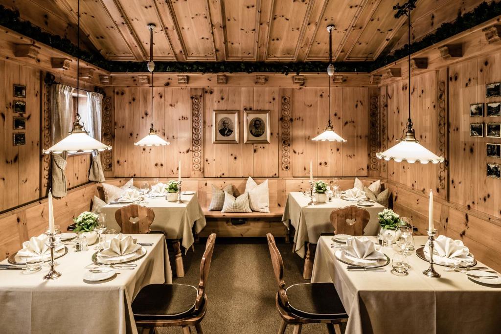 a dining room with tables and chairs and wooden walls at Hotel Alpenroyal - The Leading Hotels of the World in Selva di Val Gardena
