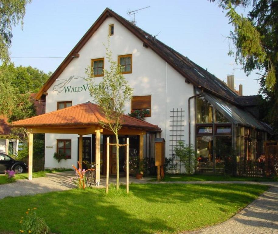 een wit huis met een boom ervoor bij Hotel Waldvogel in Leipheim