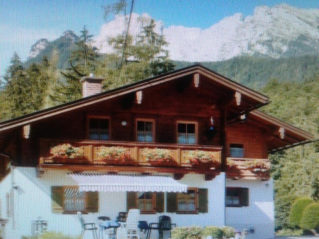 ein Haus mit einem Balkon mit Tischen und Stühlen in der Unterkunft Lärcheck in Ramsau bei Berchtesgaden
