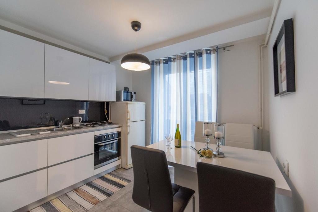 a kitchen with white cabinets and a table with chairs at Apartman Lux in Daruvar