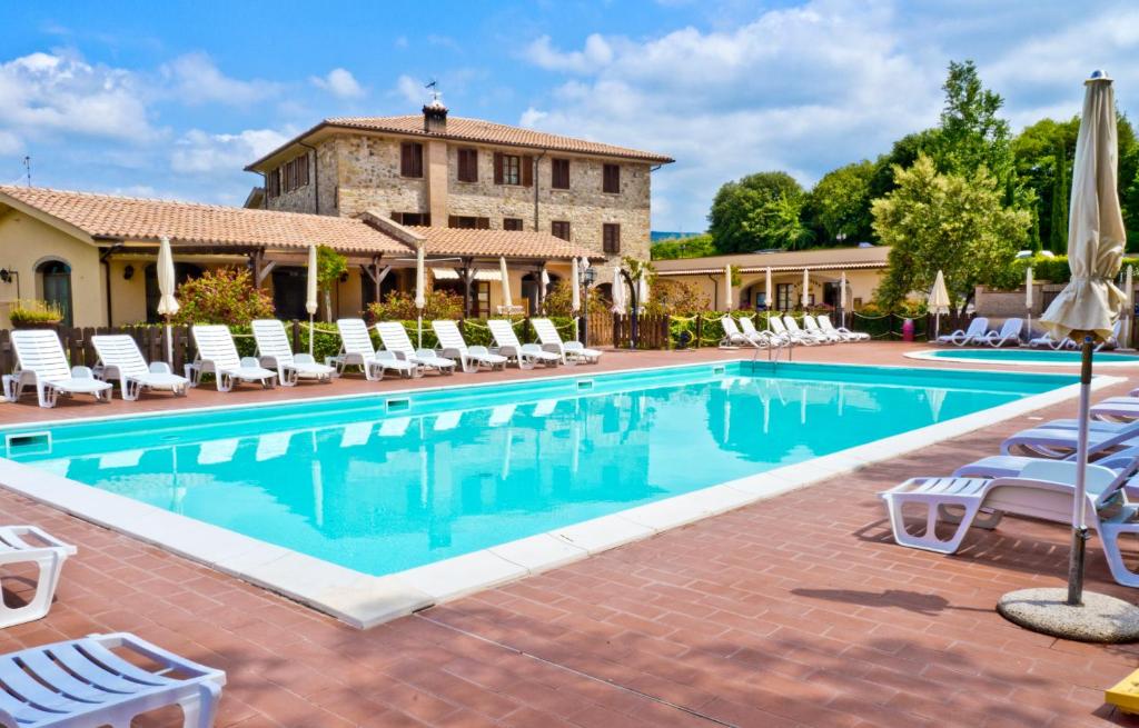 a swimming pool with chairs and a building in the background at Borgo di Pomaia in Pomaia