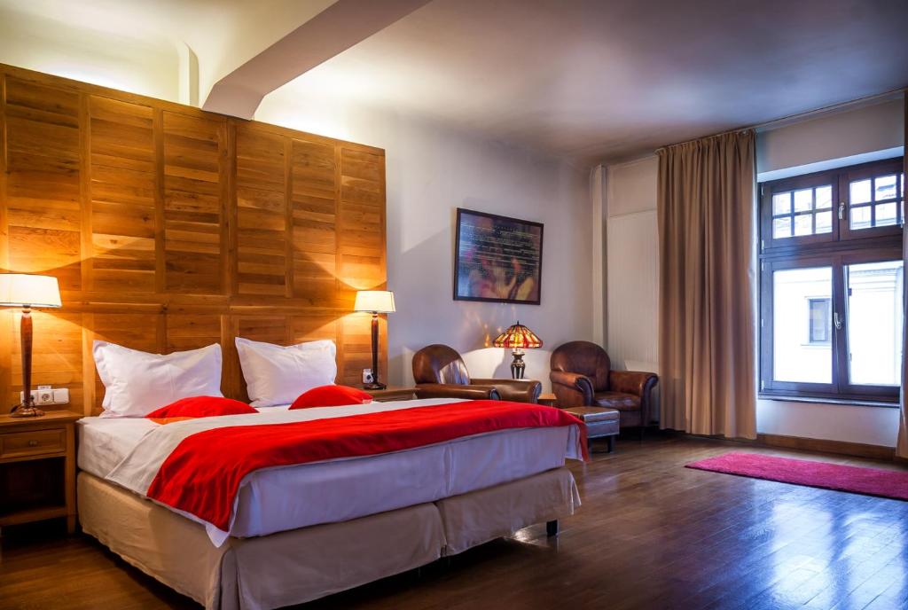 Schlafzimmer mit einem großen Bett mit einem Kopfteil aus Holz in der Unterkunft Rembrandt Hotel in Bukarest